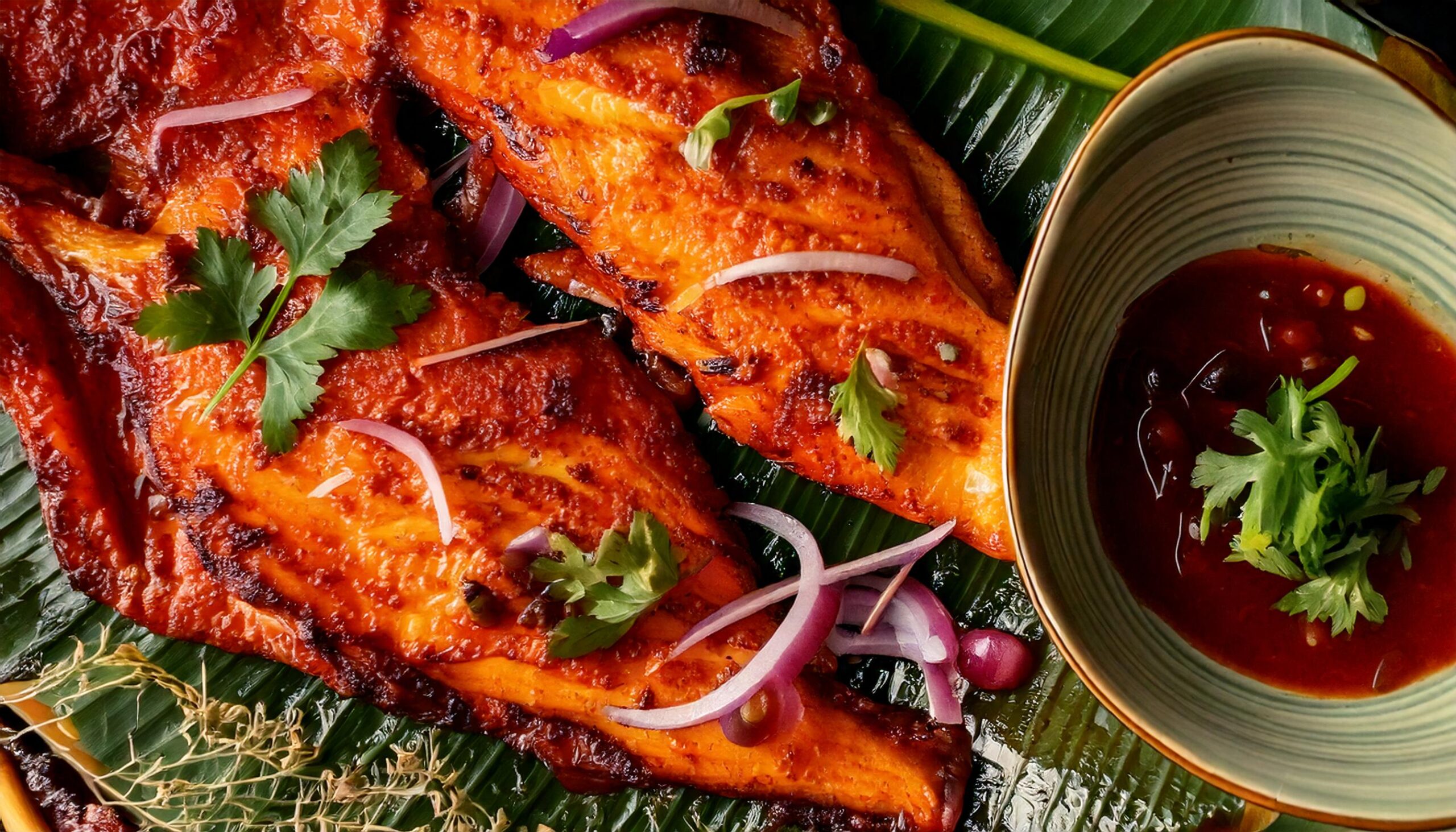 Firefly PLATILLO DE PESCADO GUISADO SERVIDO EN OJA DE PLÁTANO, ACOMPAÑADO DE CEBOLLA EN RODAJAS CON